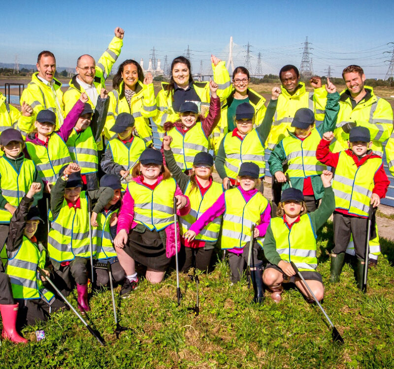 Group of adults and children wearing high-vis jackets and smiling